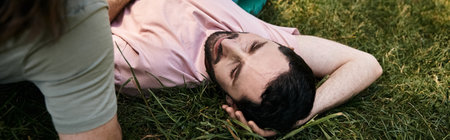 A young gay couple enjoying a summer hike together, lying down in the grass to soak up the sun.