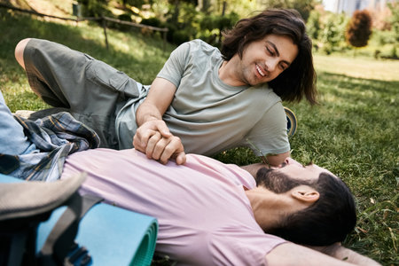 A young gay couple enjoys a romantic moment together while hiking in the wilderness during a summer...