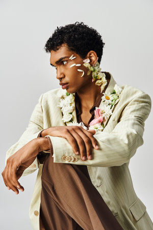 A young African American man poses in a stylish blazer, adorned with flowers on his neck and face.