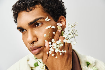 A young African American man poses with flowers on his face and neck, showcasing beauty and diversity.の写真素材
