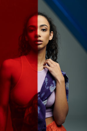 A young woman in athletic wear stands with a red pane of glass behind her, while a blue pane is...