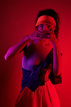A young woman poses in a studio bathed in vibrant neon lights, her style blending sport and fashion.の写真素材
