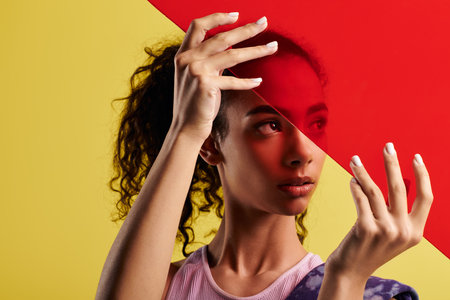 A young woman poses in a studio with colorful red glassの写真素材