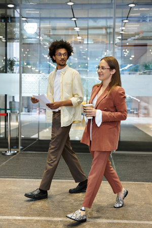 Two colleagues, one with a prosthetic leg, chat and walk through an office lobby.