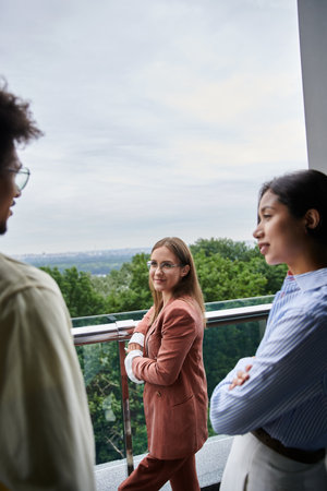 Diverse group of colleagues enjoy a conversation on a rooftop terrace overlooking the city.の写真素材