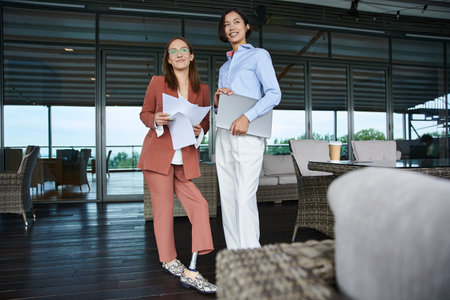 Two colleagues, one with a prosthetic leg, chat on a rooftop terrace at their modern office.の写真素材