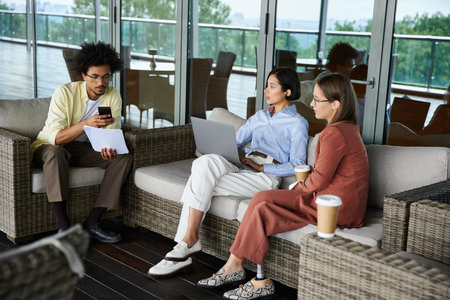 Three colleagues enjoy a relaxed conversation on a rooftop terrace.の写真素材