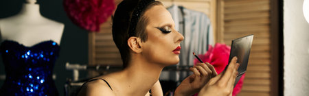 A drag queen applies lipstick while looking in a mirror, backstage before a performance.