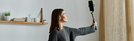 A young woman films content for her online audience while working remotely from her home.の写真素材
