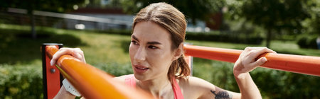 A young woman with vitiligo, wearing a pink crop top and activewear, performs a pull-up exercise...