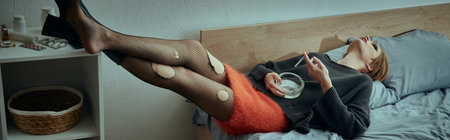 A woman in stylish grungy attire lounges on a bed, relaxing in a comfortable and casual setting.の写真素材