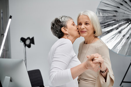 Two women, a photographer and her model, share a tender moment in a photo studio.の写真素材