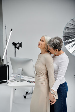 A lesbian couple poses in a photo studio, one acting as the photographer while the other is the model.の写真素材