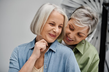 Two mature women share a loving moment in a photo studio.の写真素材