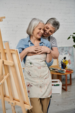 Couple embraces in art studio with woman in paint-splattered apron, both smilingの写真素材