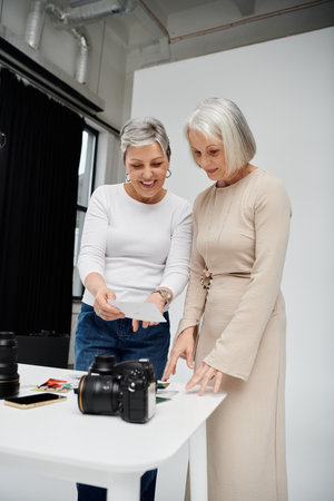 A lesbian couple, one a photographer and the other a model, examine proofs from a studio photoshoot.の写真素材