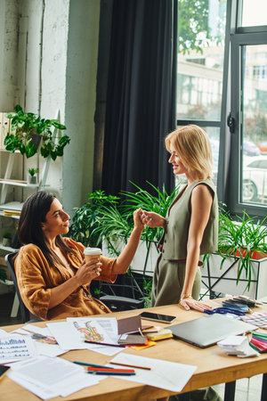 lesbian couple, dressed in smart casual attire, collaborate on a project in a modern agency office.の写真素材
