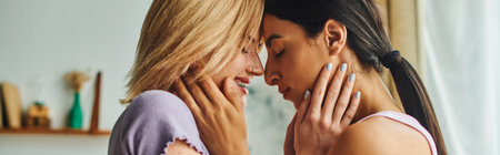 Two women, one with blonde hair and the other with dark hair, hug and smile at each other in a cozy home setting.の写真素材