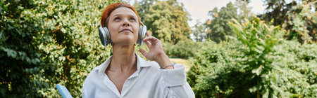 A woman wearing headphones walks through a leafy campus.の写真素材