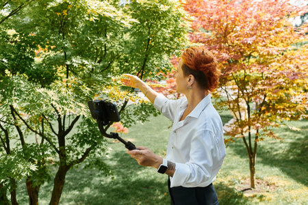 On campus, a teacher reaches for a tree, capturing the moment on her phone
