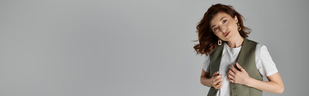 A stylish Asian woman in a vest poses against a grey background.の写真素材