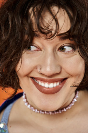 A woman with dark curly hair smiles brightly, wearing a colorful necklace.の写真素材