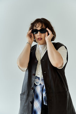 A woman wearing a leather vest and sunglasses looks confidently at the camera.の写真素材