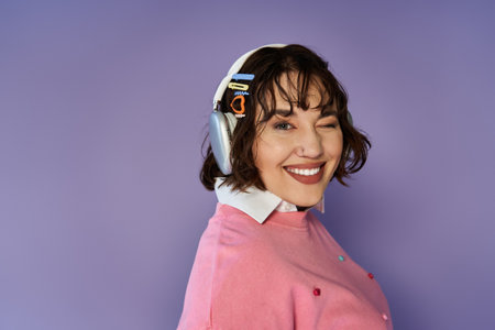 A smiling woman wearing headphones winks at the camera.の写真素材