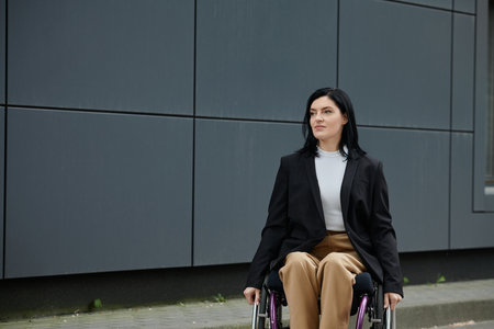 A woman in a wheelchair, dressed in a suit, looks confidently ahead in an urban setting.の写真素材