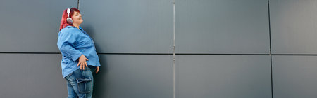 A plus size woman in bright clothes, headphones on, smiles in front of a modern backgroundの写真素材