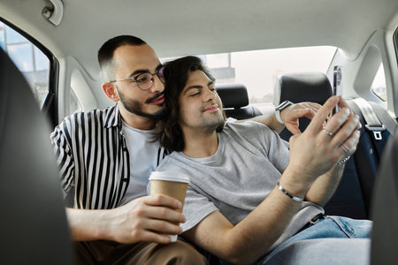 Two men take a selfie in the backseat of a car.