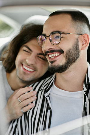Two men, happily together, share a laugh in a car.の写真素材