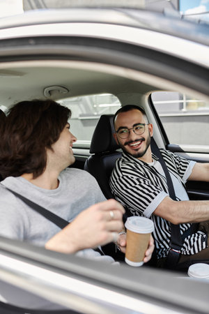 Two men smile at each other while driving in a car.