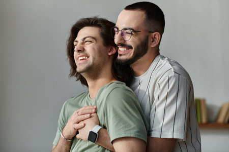 Two men in a loving embrace, sharing a laugh and a moment of joy.の写真素材