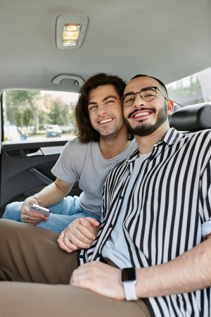 A gay couple smiles for a photo in the backseat of a car.