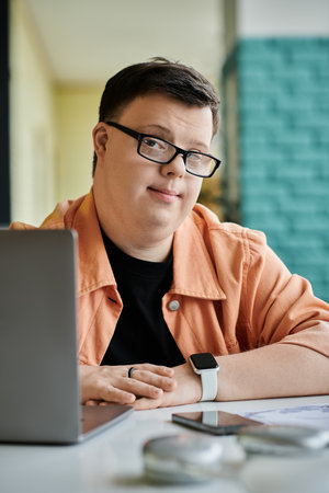 A man with Down syndrome works on his laptop in a cafe, demonstrating the power of inclusion in the...