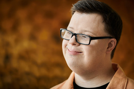 A man with Down syndrome smiles contentedly as he enjoys his dayの写真素材