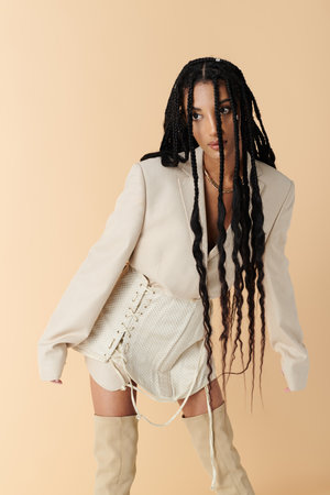A fashionable young African American woman poses confidently in a white blazer and skirt, her long...
