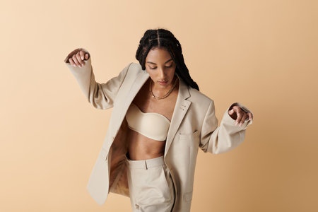 A young African American woman in her 20s poses in a stylish beige suit, exuding confidence and elegance.の写真素材