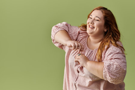 A woman smiles brightly in a pink blouse against a green background.の写真素材