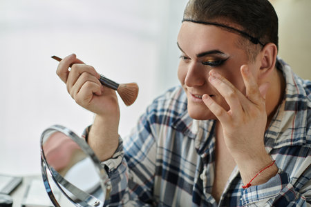 A young queer person applies makeup in front of a mirror.の写真素材