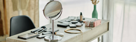 A vanity table is set with makeup, brushes, and a large round mirror.の写真素材