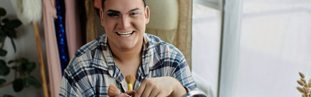 A queer person with stylish makeup and clothing applies makeup while smiling.の写真素材