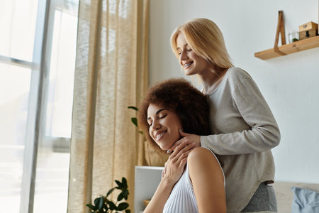 A multicultural lesbian couple enjoys a relaxing moment at home, one woman gently massaging the other neck.の写真素材