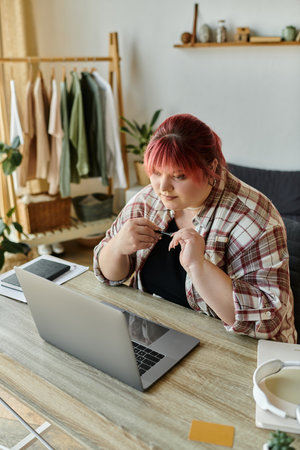 A plus size woman sits at her desk, working on her laptop.