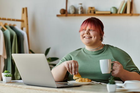 Woman smiles at table, enjoying a snack and coffee, gazing awayの写真素材