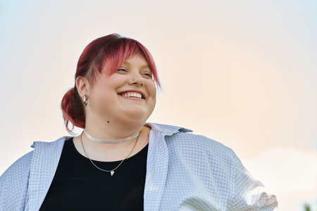A woman with pink hair looks up and smiles against a bright, hazy sky.