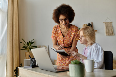 A multicultural lesbian couple works together on a project at their home office.の写真素材