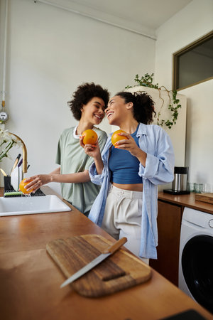 Two women share smiles and laughter while preparing fresh oranges together.の写真素材