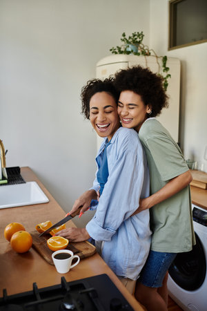 A couple shares laughter while preparing breakfast with fresh oranges.の写真素材